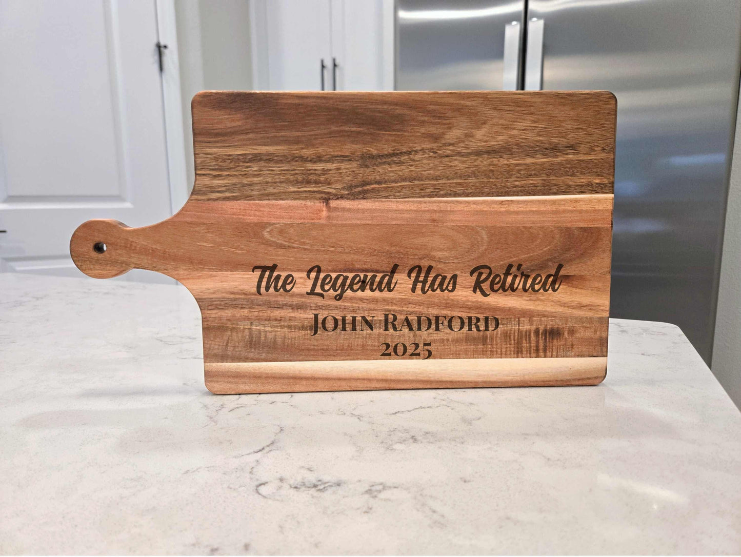 Wooden cutting board with engraved text on a marble surface